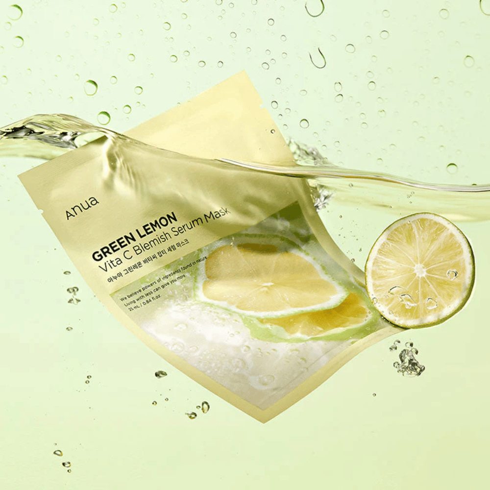 Een levendig beeld van Anua Green Lemon Vita C Blemish Serum Mask verpakking met doorzichtige waterdruppels en schijfjes groene citroen eromheen. De verpakking is gedeeltelijk bedekt door een stroom water op een lichtgroene achtergrond.