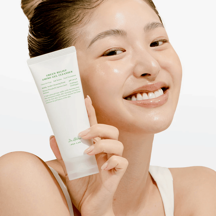 Kvinna med strålande hud håller upp Dr. Althea Green Relief Amino Gel Cleanser – vegansk rengöring för känslig och irriterad hud.