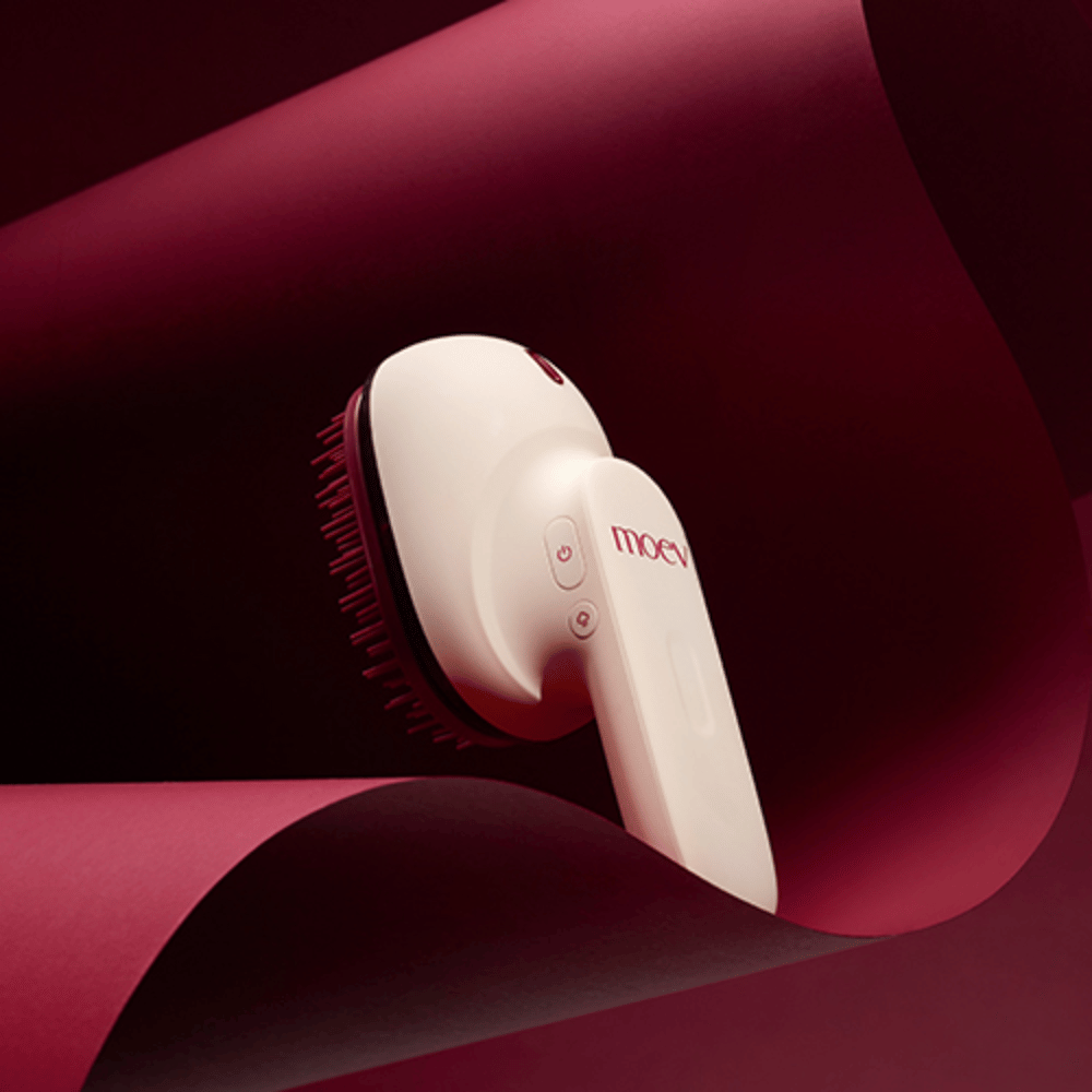 MOEV Hair Steamer Pro in elegant ontwerp tegen rode achtergrond. Innovatieve haarverzorgingsborstel die stoom en warmte gebruikt voor glans, zachtheid en versterkte haargezondheid.