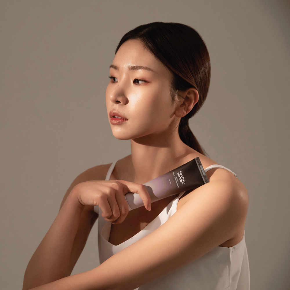 Een jonge Aziatische vrouw die een borstel in haar hand houdt terwijl ze Haruharu Wonders Black Rice Moisture 5.5 Soft Cleansing Gel 100ml gebruikt.