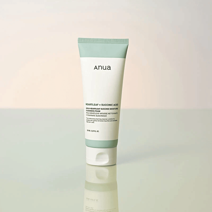 Vrijstaande productafbeelding van Anua Heartleaf + Succinic Acid Moisture Cleansing Foam. Het product wordt staand getoond op een reflecterend oppervlak dat het ontwerp van de verpakking en de strakke esthetiek van het merk duidelijk benadrukt.