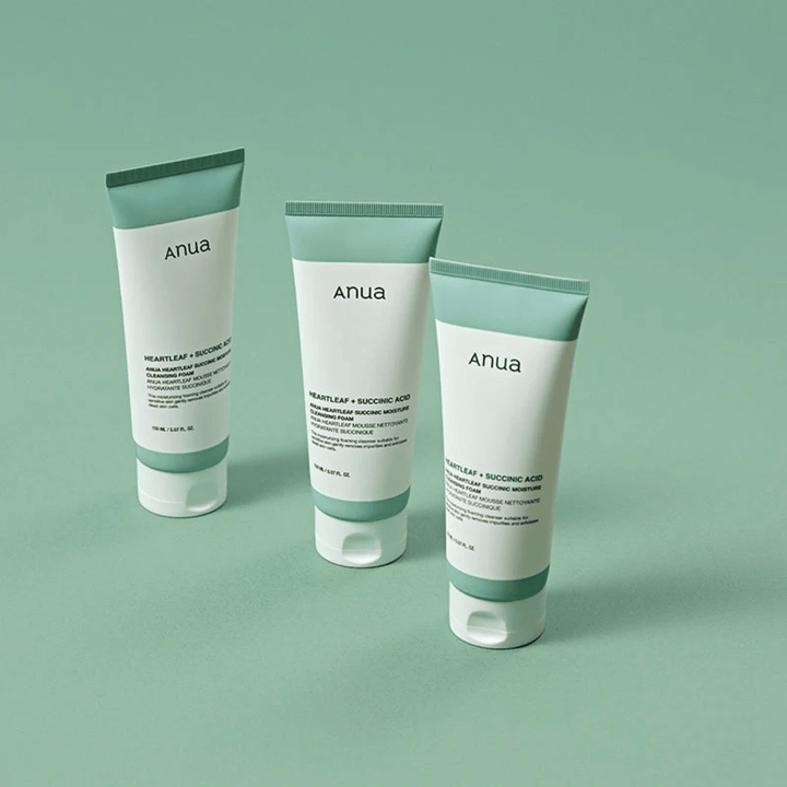 Drie verpakkingen van Anua Heartleaf + Succinic Acid Moisture Cleansing Foam gepresenteerd tegen een lichtgroene achtergrond. De afbeelding benadrukt het schone en minimalistische ontwerp van het product en geeft een professionele indruk van de productlijn.