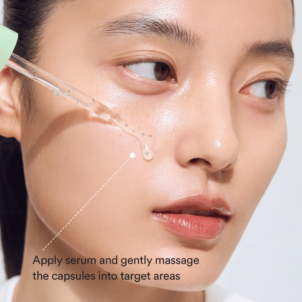 Close-up van model dat het serum met een pipet aanbrengt terwijl de groene capsules in de huid worden ingemasseerd voor een kalmerend en hydraterend effect.