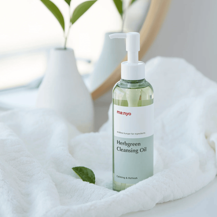 ma:nyo Herbgreen Cleansing Oil in pompflacon geplaatst op witte handdoek, kalmerende reinigingsolie met kruideningrediënten voor zachte gezichtsreiniging