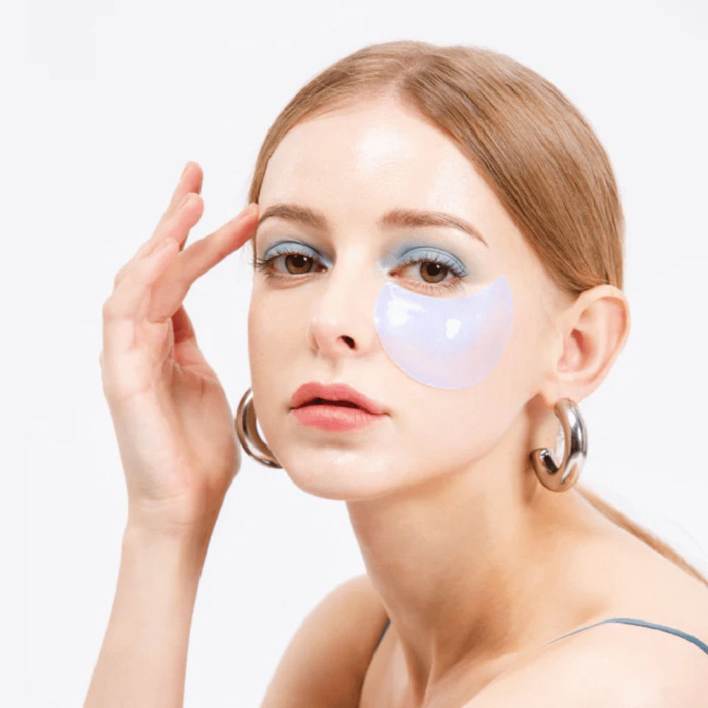 Model draagt een blauw glinsterende hydrogel oogpatch onder het oog voor een verfrissend effect.