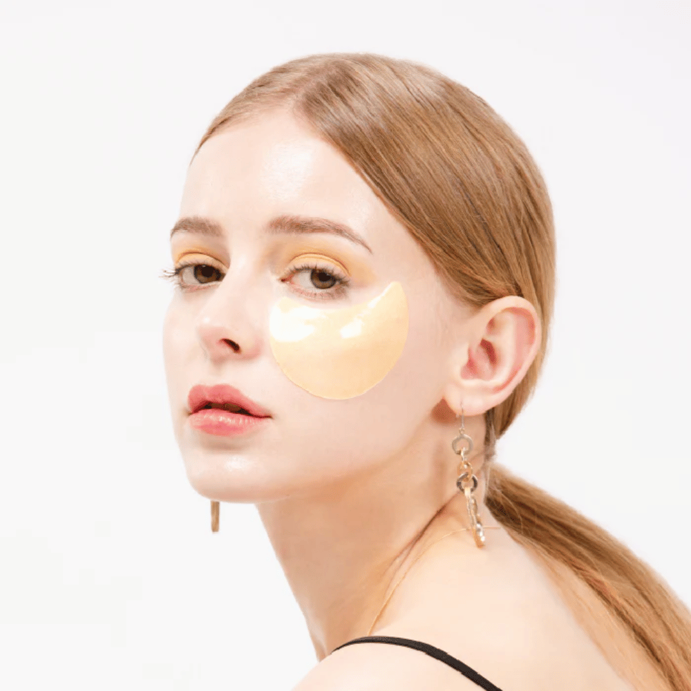 Model draagt een goudglanzende hydrogel oogpatch onder het oog voor een stralend effect.