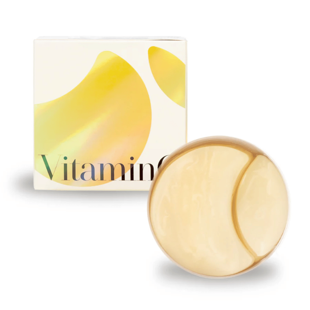 K-Secret Extra Illuminating Eye Gel Patches met vitamine C in goudglanzende hydrogel, pot en verpakking op de achtergrond.