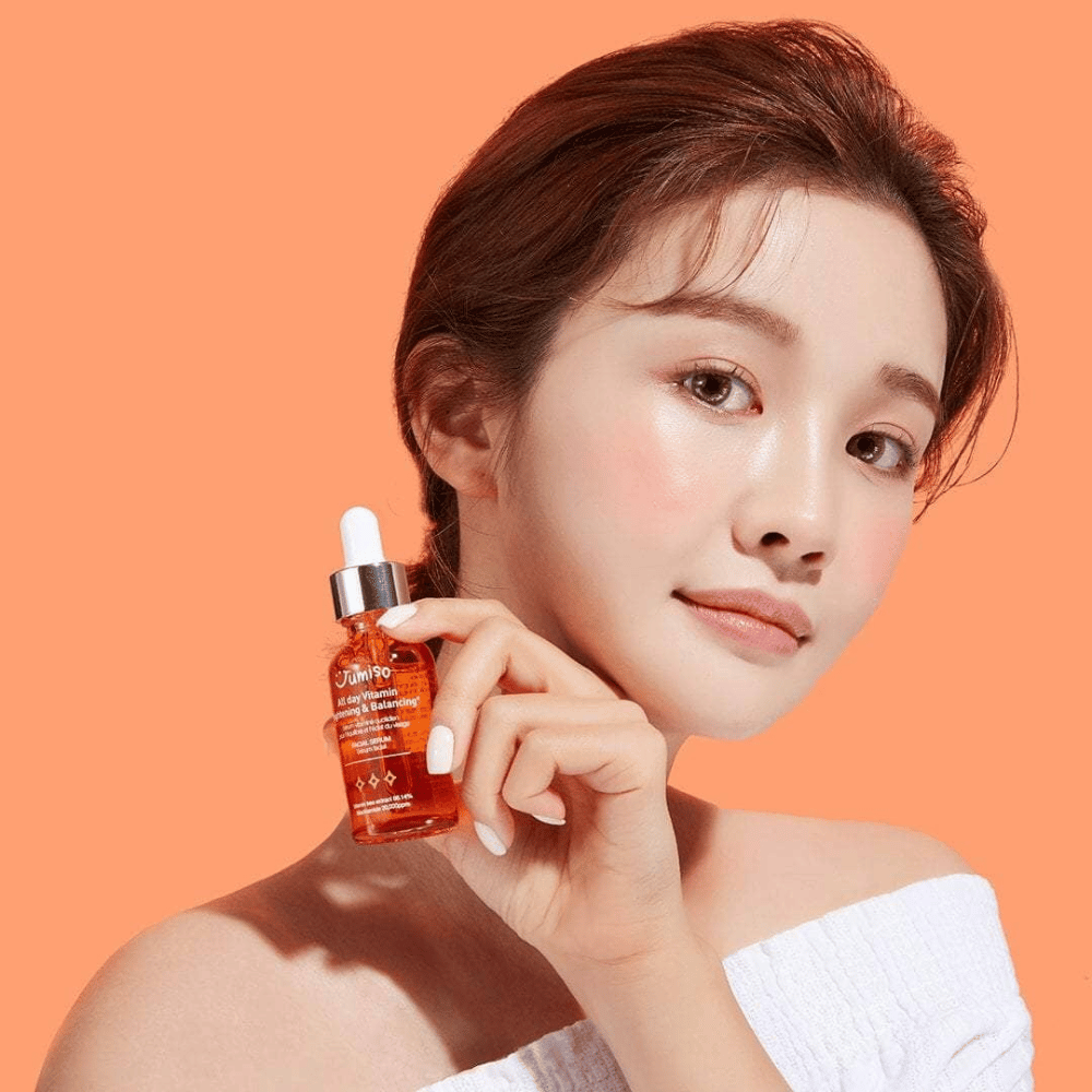 Een vrouw die een flesje JUMISO All Day Vitamin Brightening & Balancing Facial Serum 30ml vasthoudt.