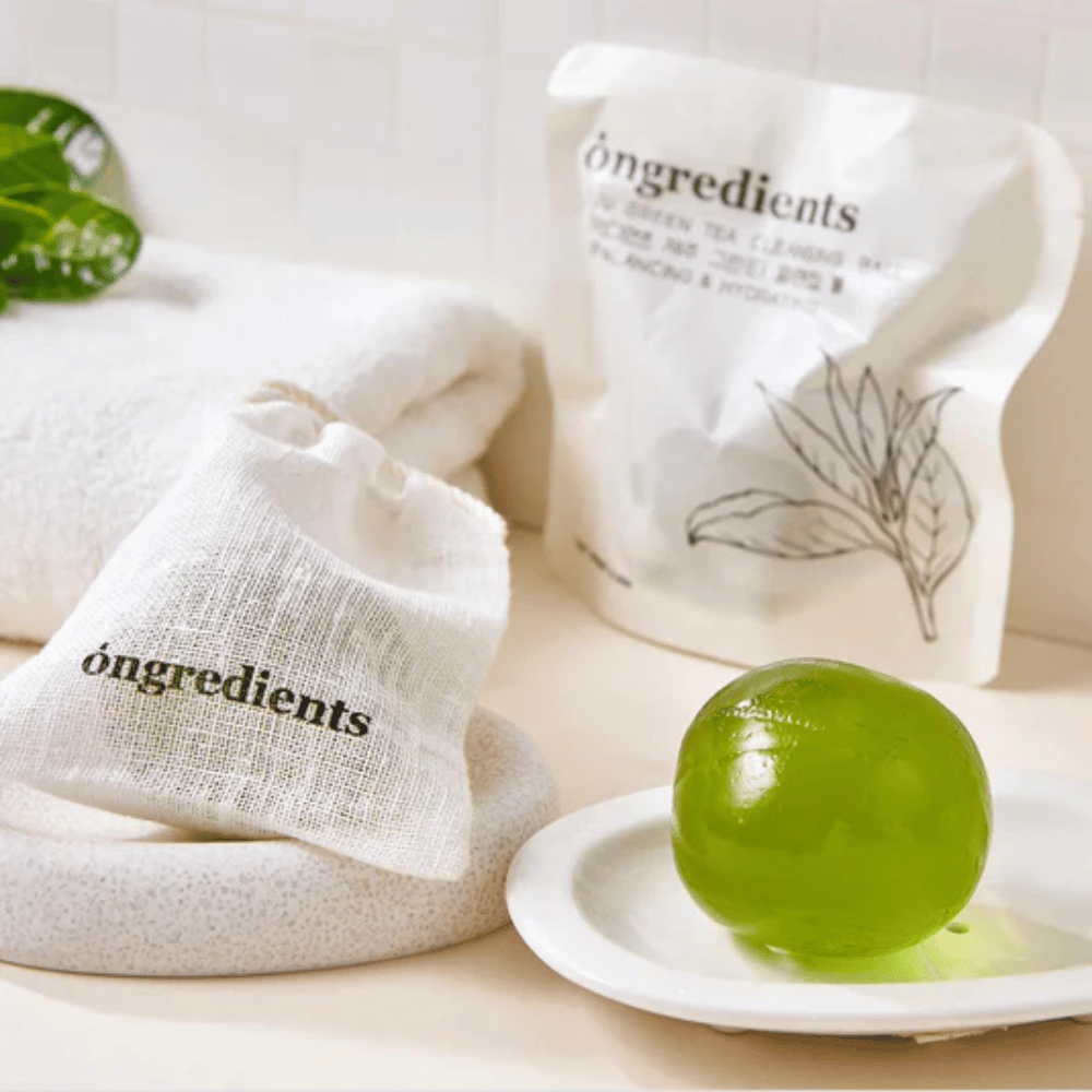 Óngredients Jeju Green Tea Cleansing Ball geplaatst op een bord met verpakking en handdoek – milde reiniging met groene thee uit Jeju.
