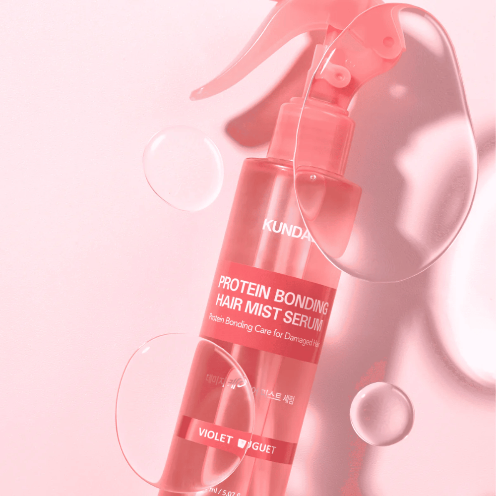 KUNDAL Protein Bonding Hair Mist Serum Violet Bouquet in roze spuitfles, gefotografeerd tegen roze achtergrond met waterdruppels.
