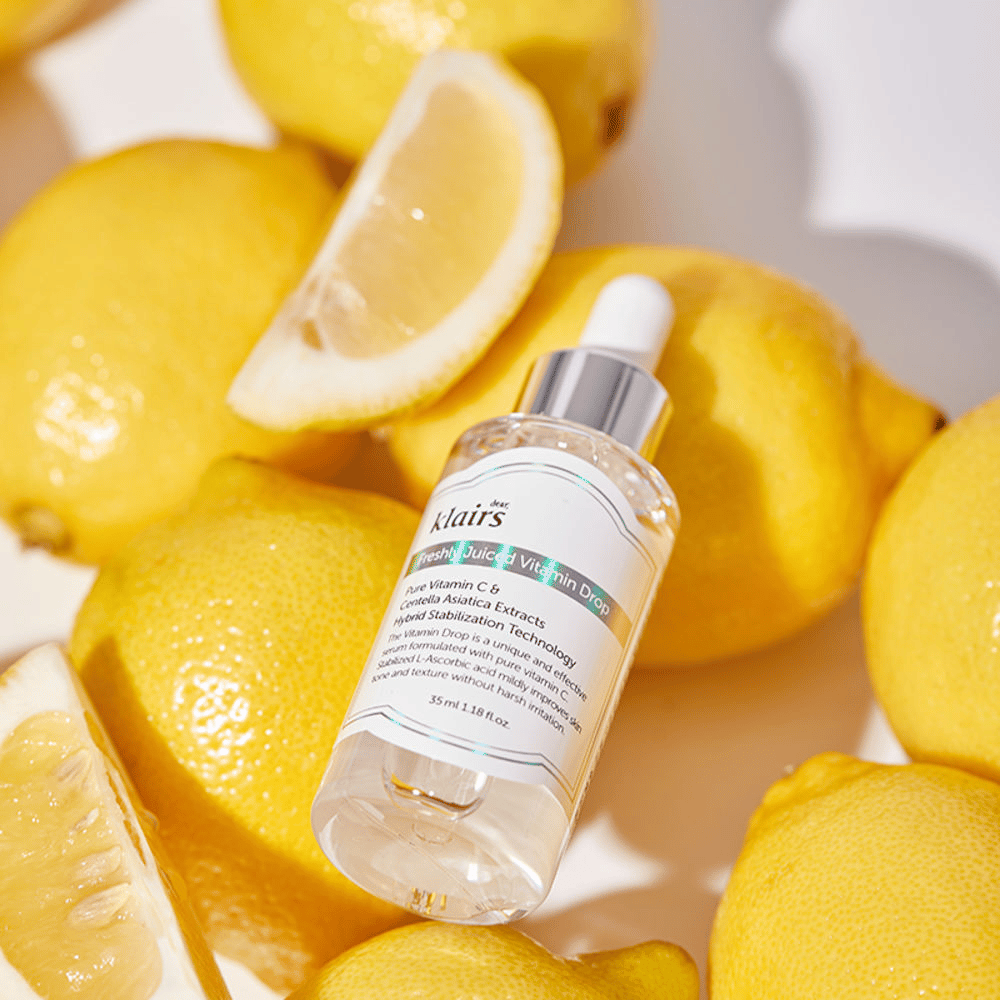 Klairs Freshly Juiced Vitamin Drop serumfles omringd door verse citroenhelften en citroenschijfjes op een lichte ondergrond, benadrukt de ingrediënten.