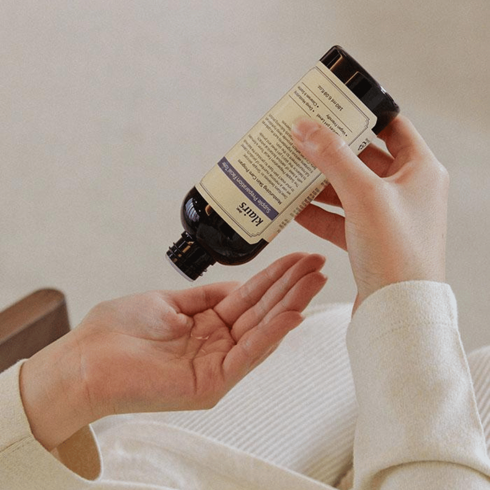 Een persoon houdt een fles van Klairs Supple Preparation Facial Toner ondersteboven boven zijn hand, klaar om het product te doseren.