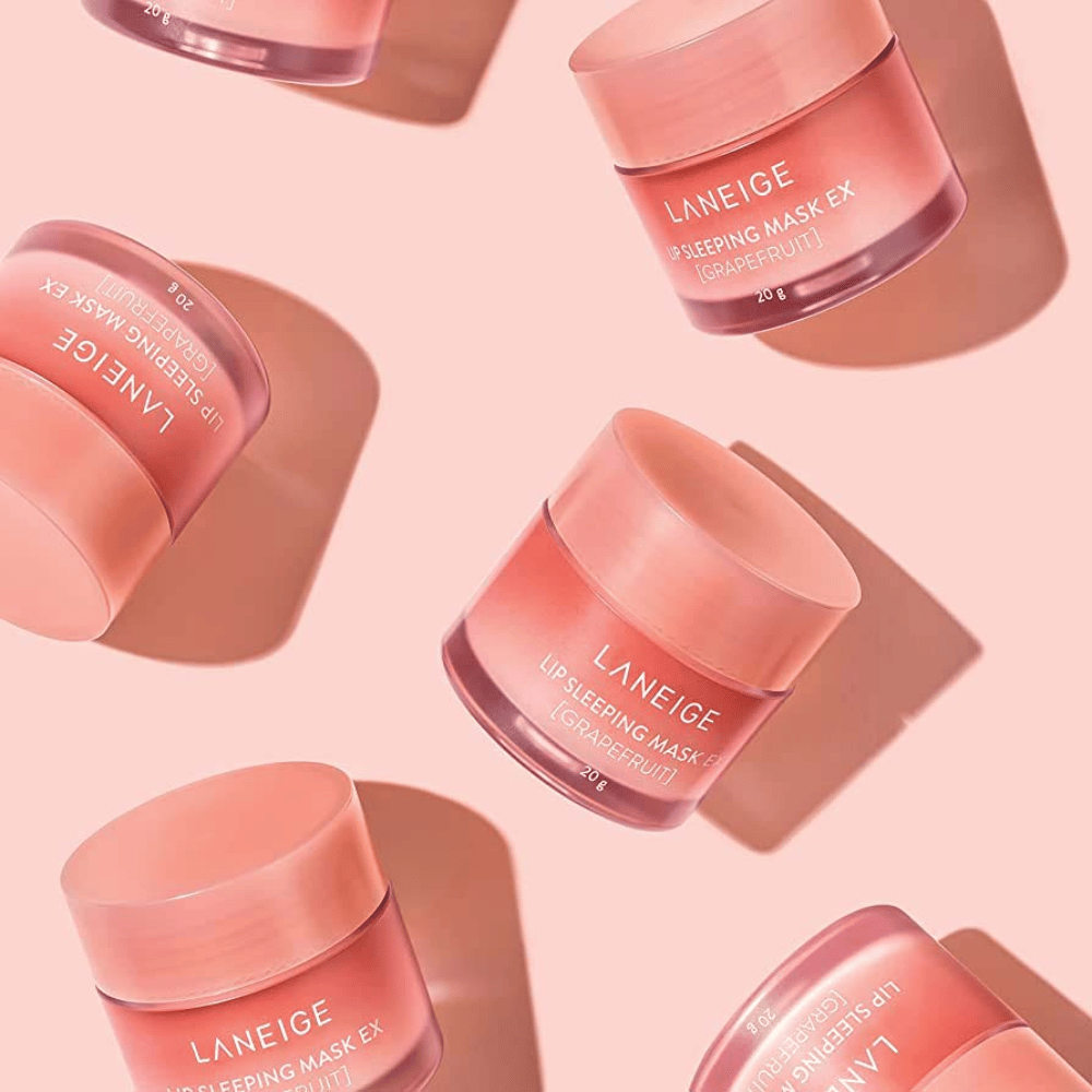 Vier potten LANEIGE Lip Sleeping Mask Grapefruit 20g op roze achtergrond, bevordert grapefruit en hydratatie.