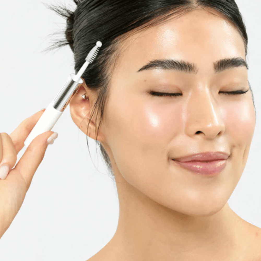 Vrouw brengt Seapuri Lashrum Eyelash Enhancing Serum aan op wimpers. Bevordert natuurlijke groei en glans.