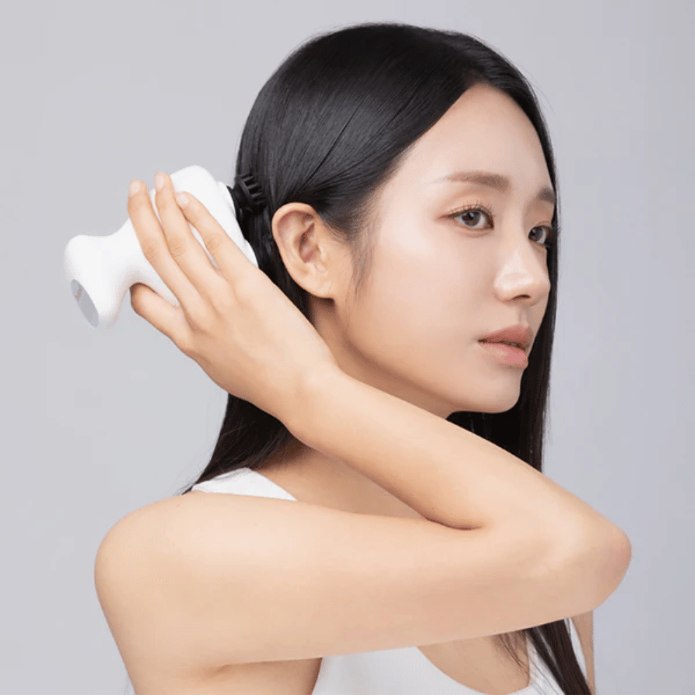 Model gebruikt Beaund Lift Head Spa direct op de hoofdhuid achter het oor. De afbeelding demonstreert hoe het apparaat wordt gebruikt om de hoofdhuid te masseren en een aangename stimulatie te geven.