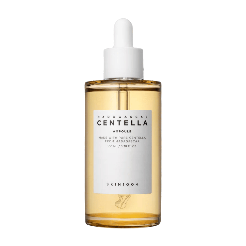 De afbeelding toont een fles met "Madagascar Centella Asiatica 100 Ampoule" van SKIN1004. De fles bevat 100 ml en beweert gemaakt te zijn met pure Centella uit Madagaskar. Het product lijkt een huidverzorgingsserum te zijn en het eenvoudige etiket geeft een indruk van zuiverheid en natuurlijkheid. De fles met druppeldop suggereert dat dit een zorgvuldig gedoseerd huidverzorgingsproduct is.