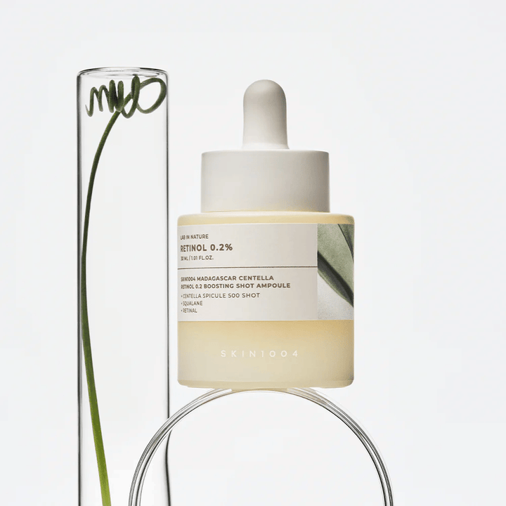 SKIN1004 Madagascar Centella Retinol 0.2 Boosting Shot Ampoule in een lifestyle-afbeelding met botanische elementen – gezichtsserum dat de huidvernieuwing ondersteunt en de huidbarrière versterkt.