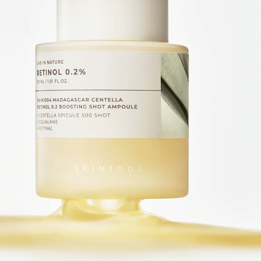 Close-up van SKIN1004 Madagascar Centella Retinol 0.2 Boosting Shot Ampoule die de lichtgele, zijdezachte textuur van het retinolserum voor nachtelijke huidvernieuwing toont.