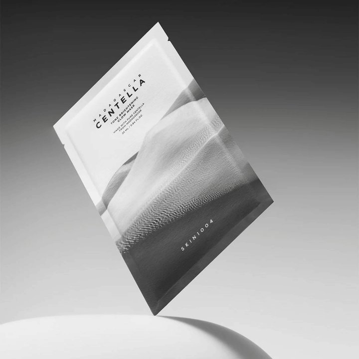 Sheet mask-verpakking van SKIN1004 zwevend tegen een grijze achtergrond met minimalistisch ontwerp.