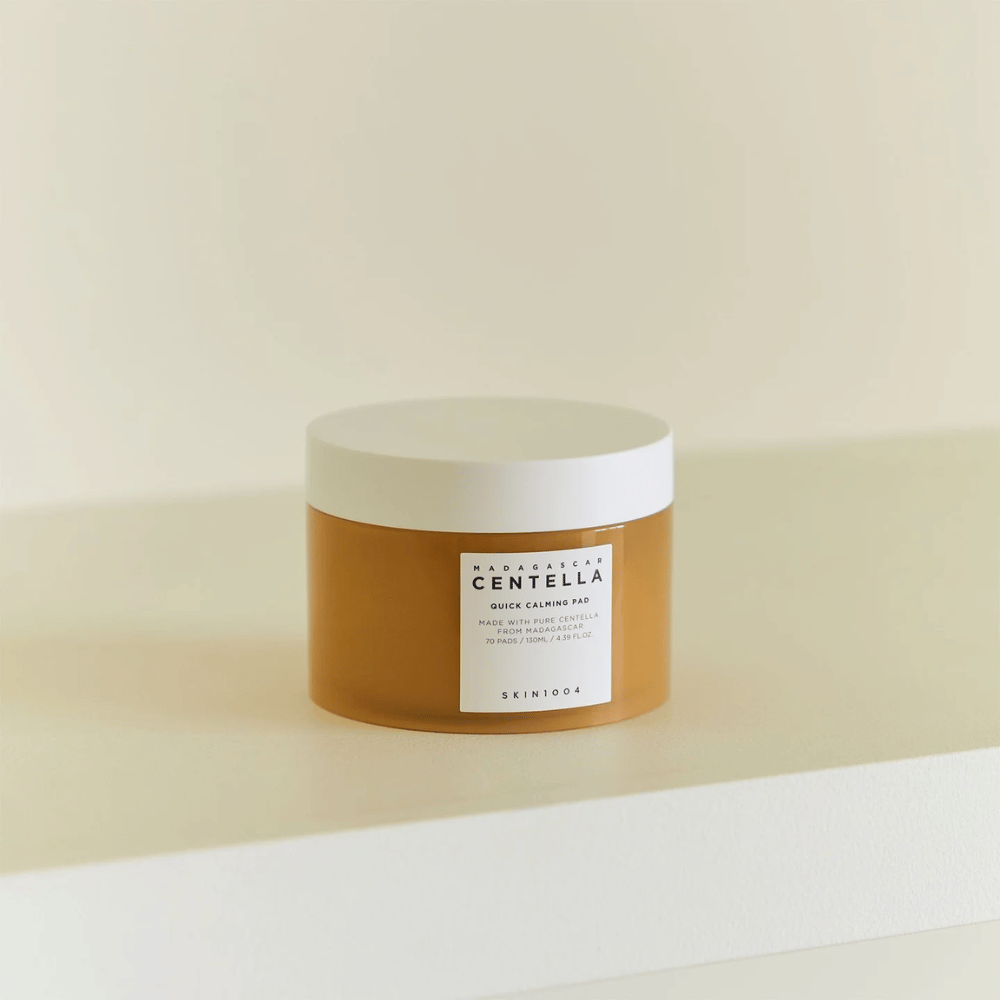 SKIN1004 Madagascar Centella Quick Calming Pad geplaatst op een witte plank – amberkleurige pot met wit deksel en duidelijk etiket aan de voorkant.