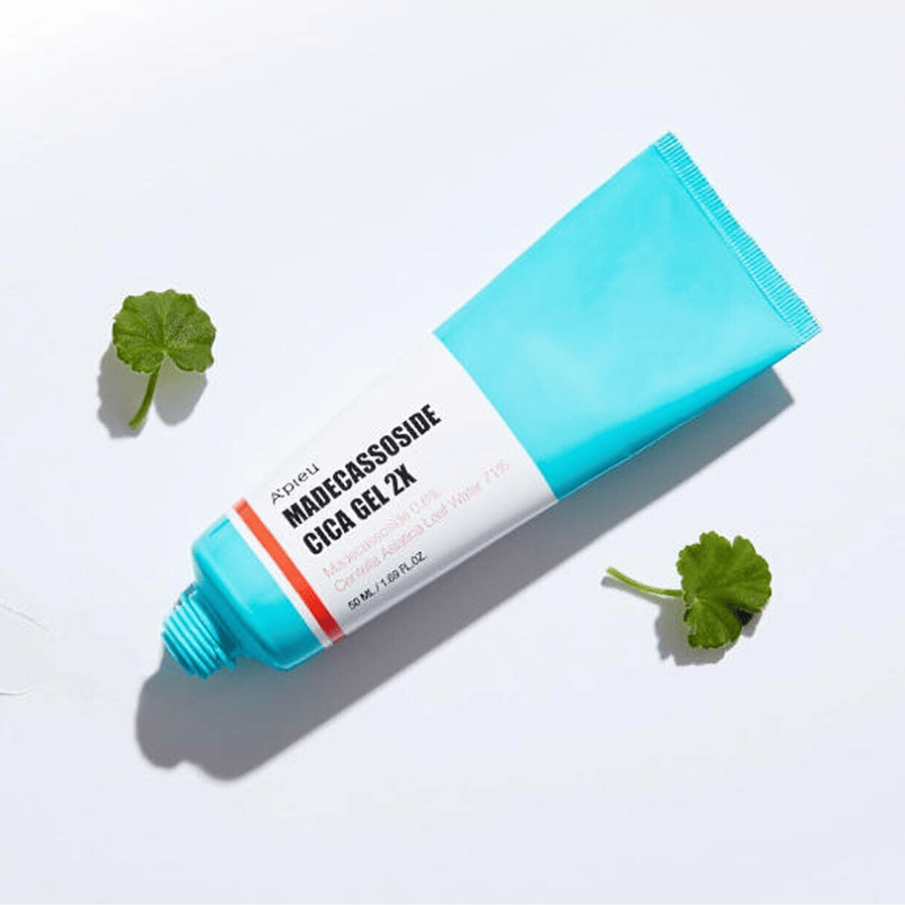 A’pieu Madecassoside Cica Gel 2X in een blauwe tube met wit etiket, omringd door drie groene centella asiatica-bladeren op een witte achtergrond.