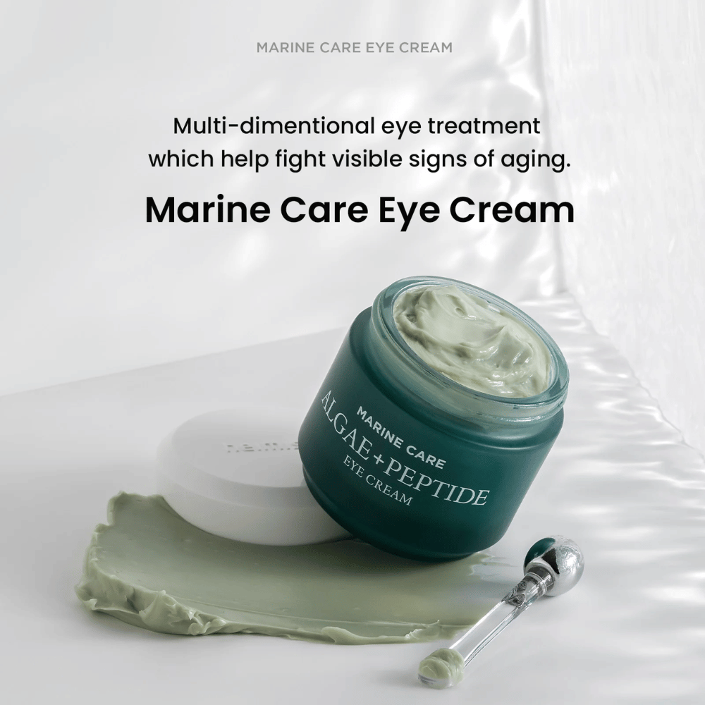 Heimish Marine Care Algae + Peptide Eye Cream in een open pot met groenige crème. De crème is uitgesmeerd naast de pot en een applicator ligt ernaast. Het product bestrijdt tekenen van veroudering en biedt intense hydratatie.