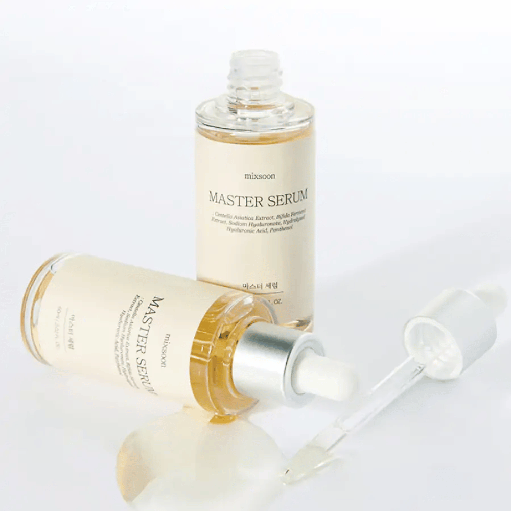 Twee flessen Mixsoon Master Serum, één staand en één liggend met een open pipet, waarbij het serum op een wit oppervlak is gemorst.