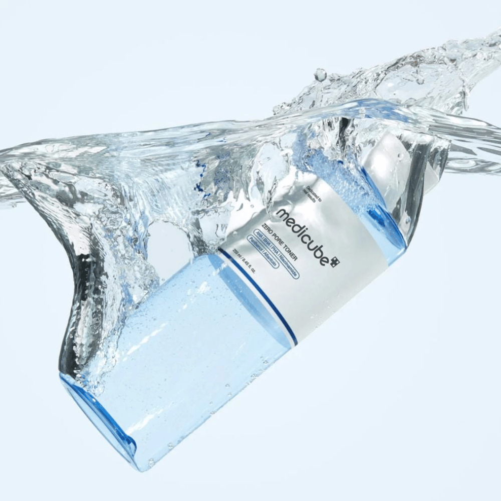 Medicube Zero Pore Toner 250 ml, exfoliërende toner met AHA, BHA en PHA. Doorzichtige blauwe fles omringd door een grote waterspat.