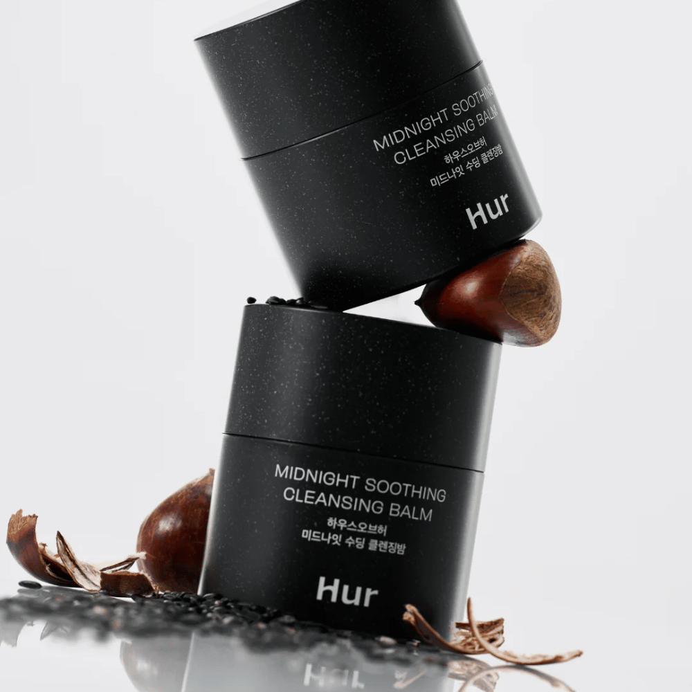 Twee potten Hoe Midnight Soothing Cleansing Balm gestapeld met natuurlijke ingrediënten. Voedende reinigingsbalsem voor dagelijkse reiniging van de gevoelige huid.