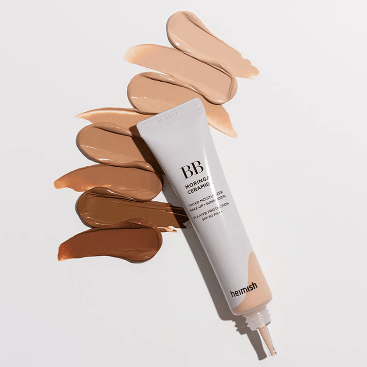 Heimish Moringa Ceramide BB Cream omgeven door meerdere kleurstalen in verschillende huidtinten. De afbeelding toont het brede kleurassortiment van het product en de romige textuur die zorgt voor een natuurlijke dekking en een egale huidtoon.