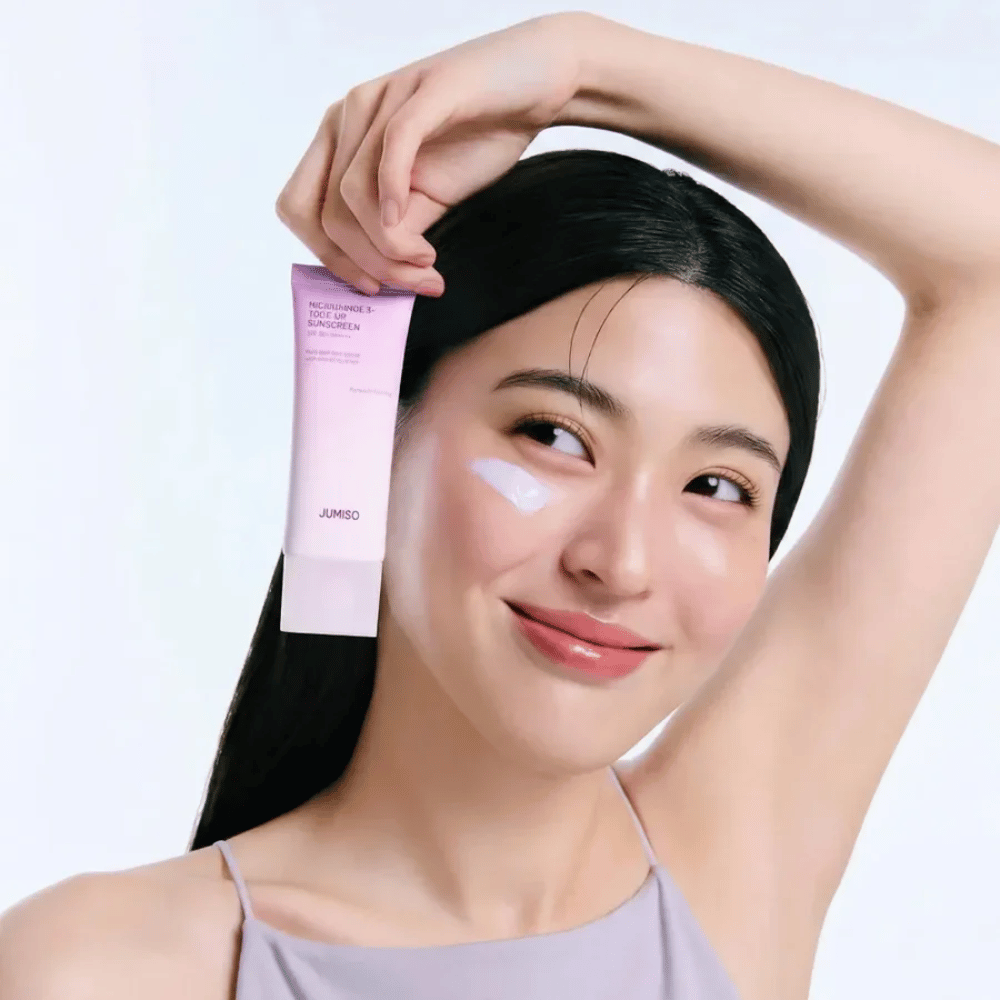 Model houdt JUMISO Niacinamide 3+ Tone-Up Sunscreen SPF50+ PA++++ vast – zonnecrème met niacinamide die de huidtoon egaliseert en de huid beschermt.