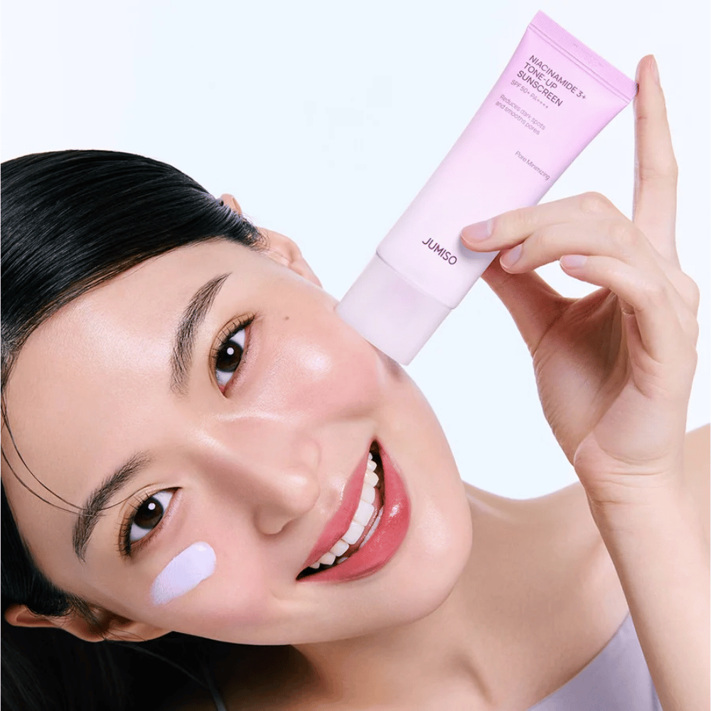 Model brengt JUMISO Niacinamide 3+ Tone-Up Sunscreen SPF50+ PA++++ aan voor UV-bescherming, een egalere huidtoon en een natuurlijke glow.