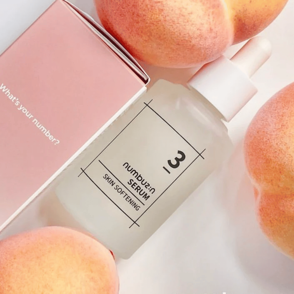 Fles met numbus:in No.3 Skin Softening Serum omringd door perziken en een roze doos met de tekst "What's your number?".
