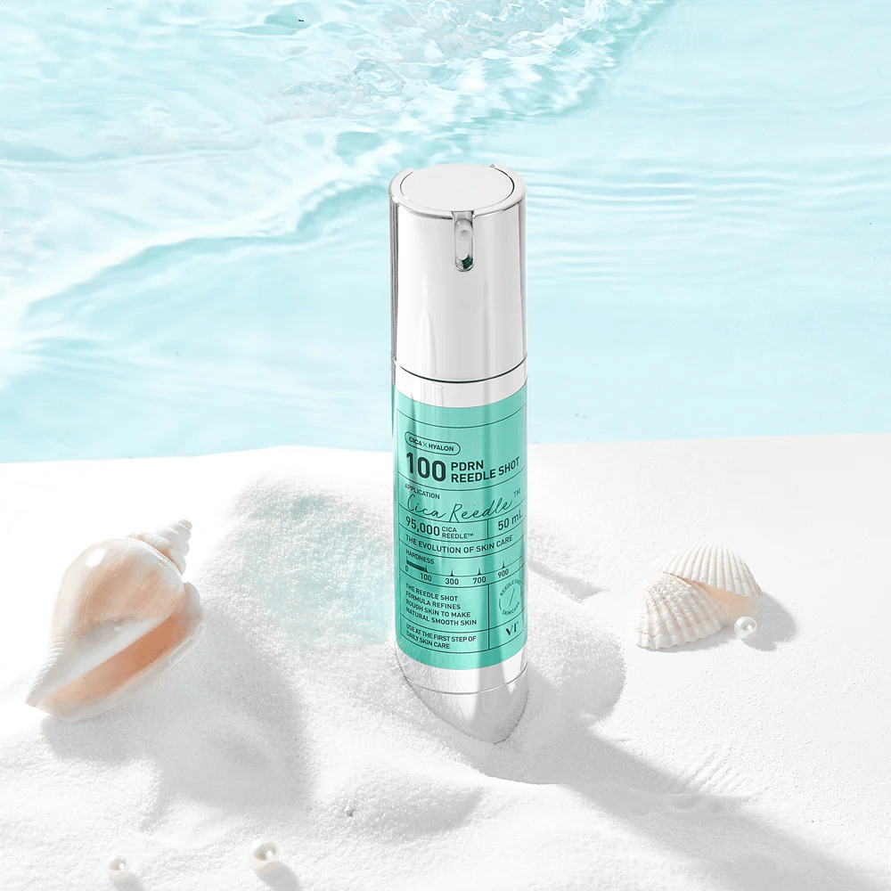 VT Cosmetics PDRN Reedle Shot 100 product geplaatst in een zandomgeving met zeethema dat hydratatie, een kalmerend effect en huidverbetering symboliseert