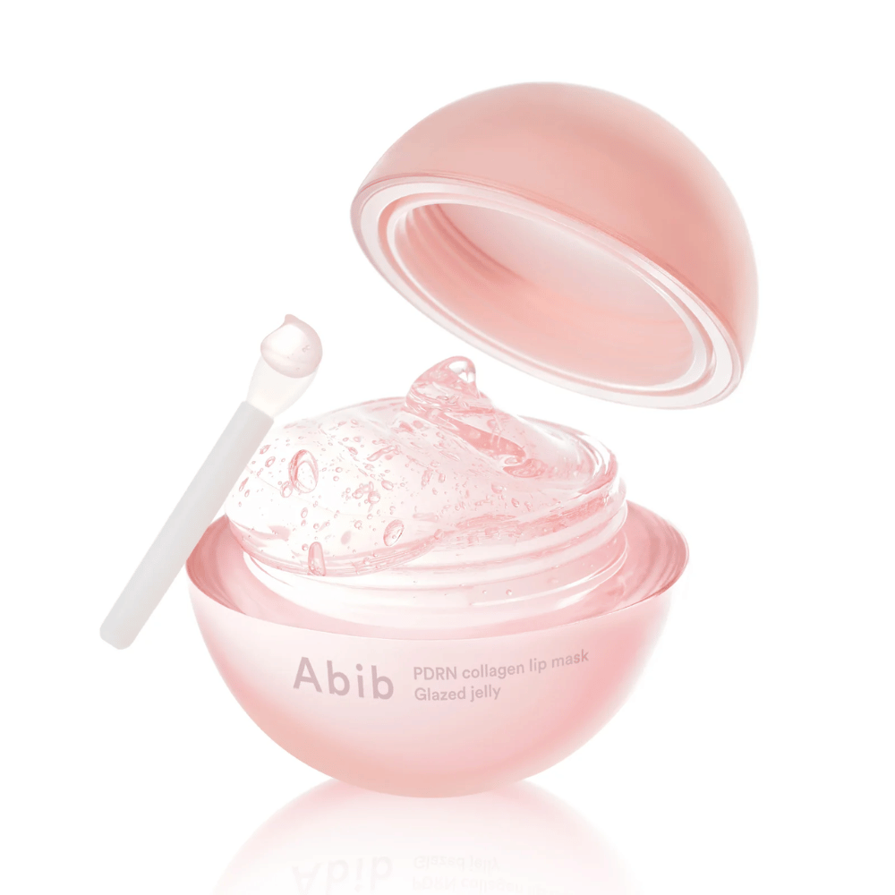 Roze ronde pot met Abib PDRN Collagen Lip Mask Glazed Jelly, open met het deksel naar achteren gekanteld. Transparante gel met luchtbellen is zichtbaar in de pot samen met een kleine spatel.