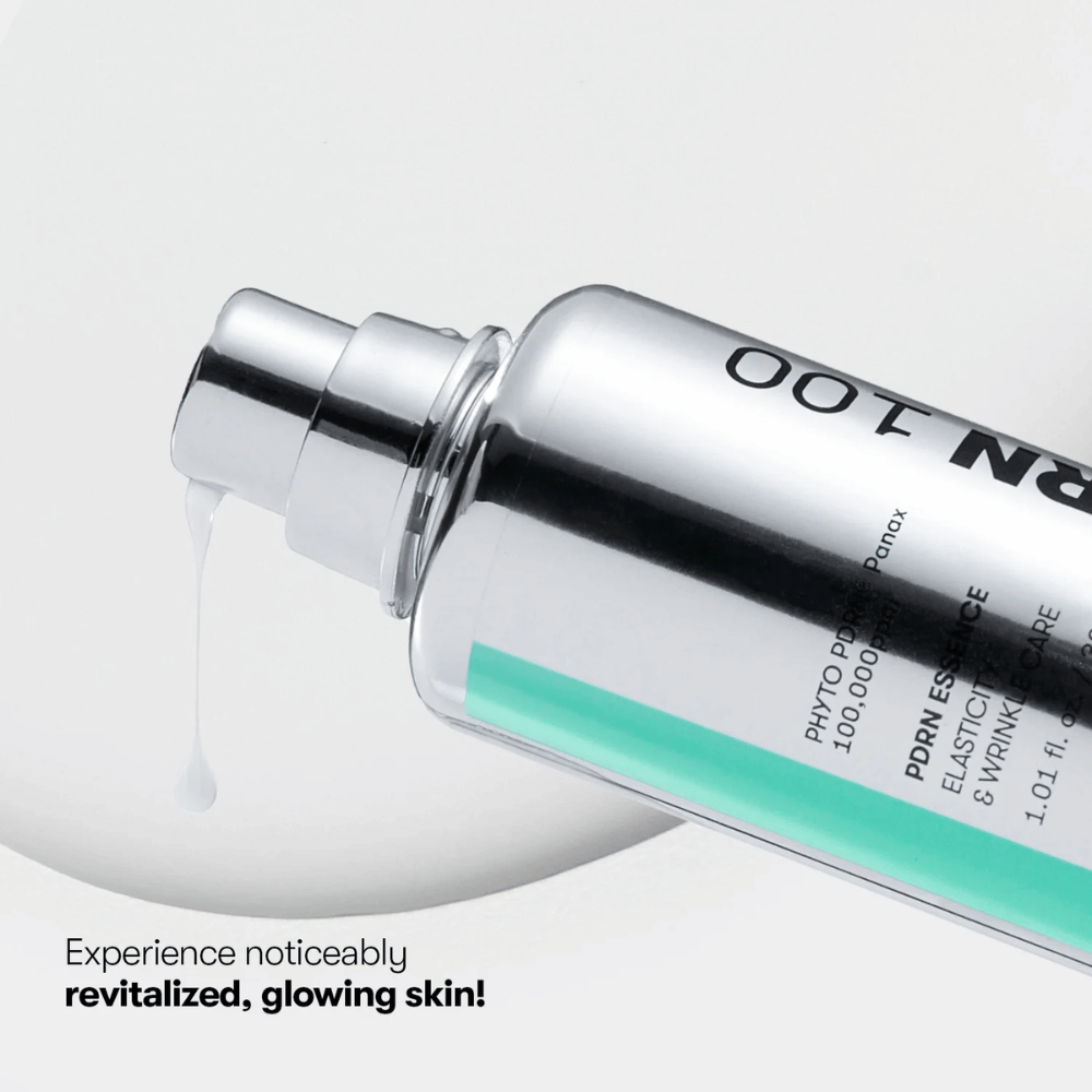 Close-up van een zilverkleurige pompflacon met VT PDRN Essence 100. Een witte essentie stroomt uit het mondstuk, en de tekst op de afbeelding luidt: "Ervaar merkbaar vernieuwde, stralende huid!"