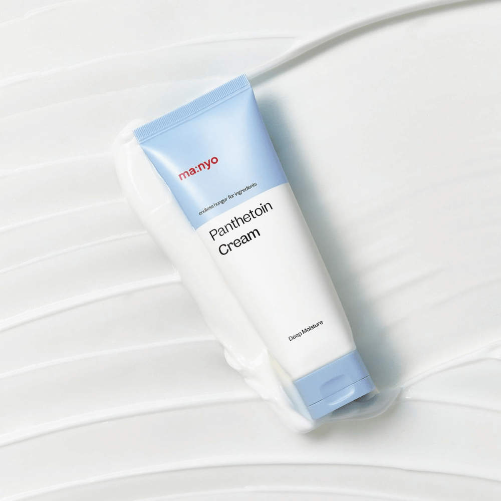 2. Ma:nyo Panthetoin Cream – hydraterende gezichtscrème in een witte en lichtblauwe tube omringd door crèmige textuur op een witte achtergrond