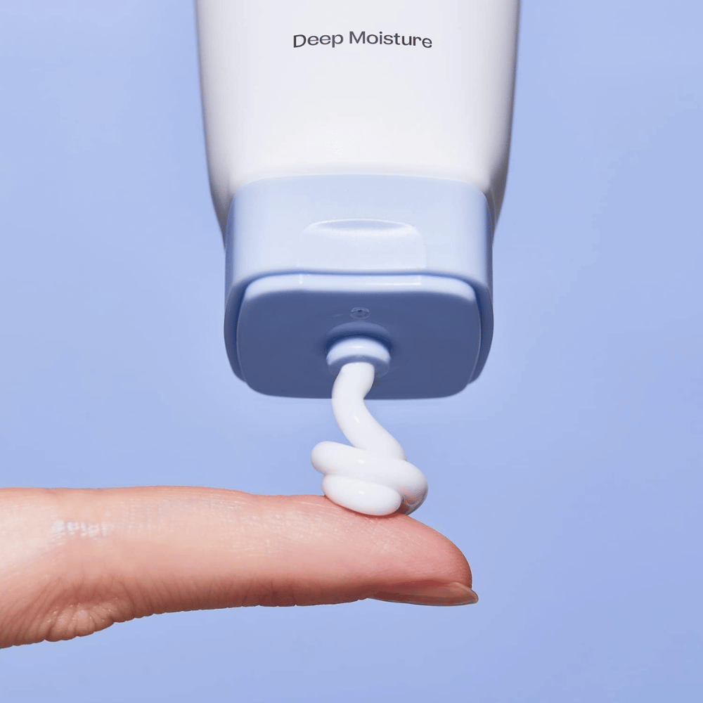 1. Ma:nyo Panthetoin Cream – close-up van witte hydraterende gezichtscrème die vanuit een lichtblauwe tube op een vinger wordt aangebracht