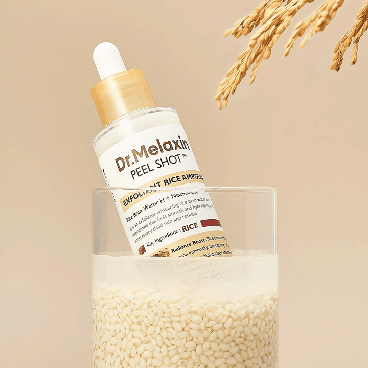 Dr.Melaxin Peel Shot Exfoliant Rice Ampoule geplaatst in glas met rijst, illustreert de glansgevende en hydraterende eigenschappen van rijstextract in Koreaanse huidverzorging.
