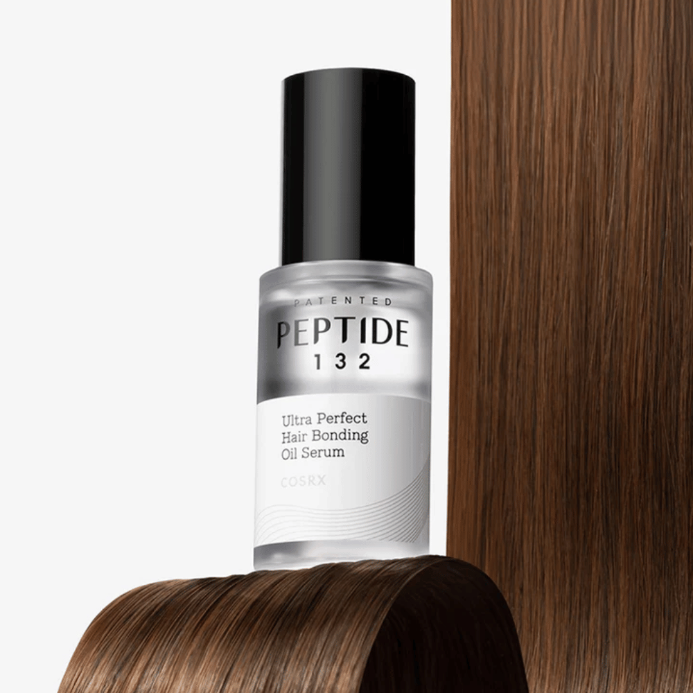 COSRX Peptide 132 Ultra Perfect Hair Bonding Oil Serum geplaatst tegen glanzend haar – biedt kracht, zachtheid en glans.