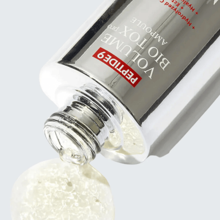 Närbild på MEDI-PEEL Peptide 9 Volume Bio Tox Pro Ampoule som hälls ut. Den klara formulan med kollagen, ectoin och hyaluronsyra återfuktar på djupet.