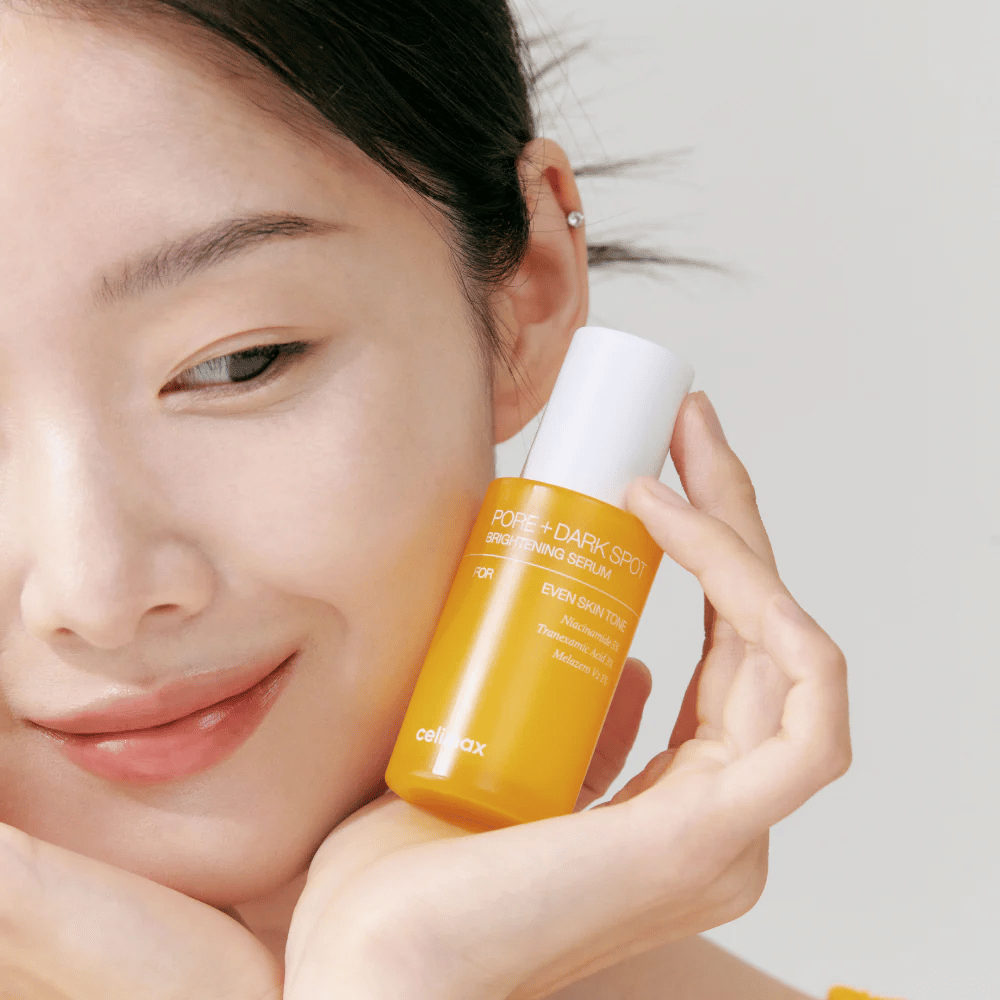 Model houdt Celimax Pore + Dark Spot Brightening Serum dicht bij het gezicht, toont stralende huid.