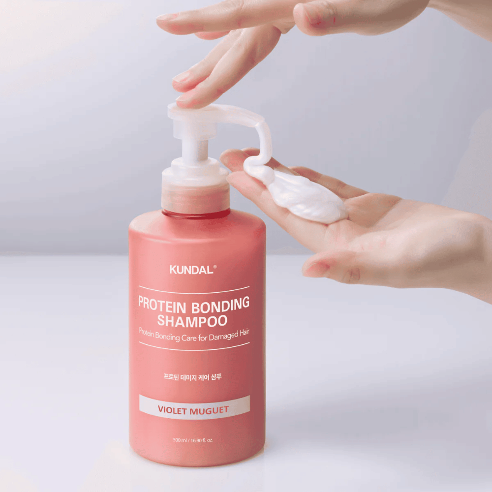 Hand pompt KUNDAL Protein Bonding Shampoo Violet Muguet in romige consistentie, herstellende shampoo voor beschadigd haar.