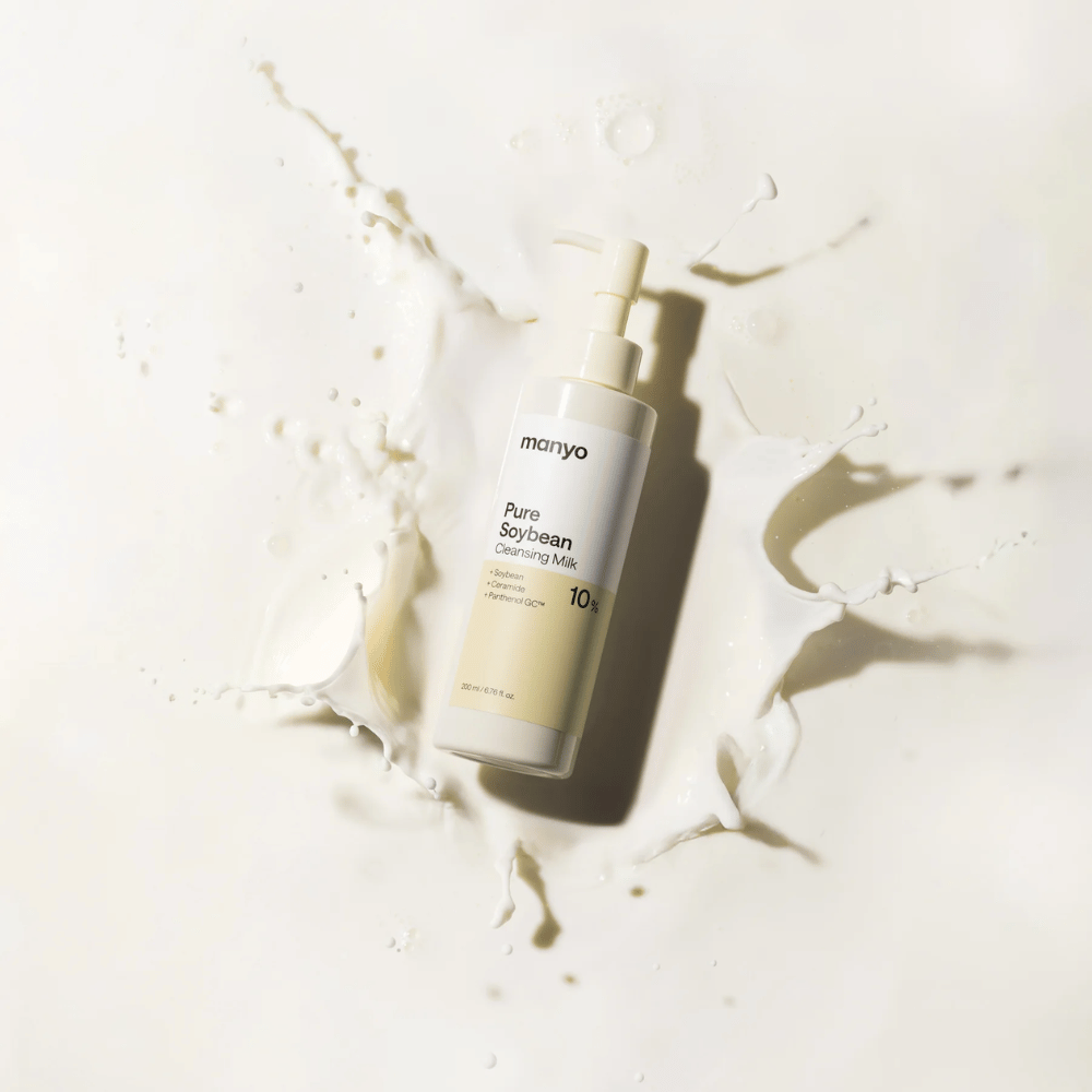 1. Ma:nyo Pure Soybean Cleansing Milk – milde reinigingsmelk met soja in pompflacon omgeven door melkspetters op lichte achtergrond
