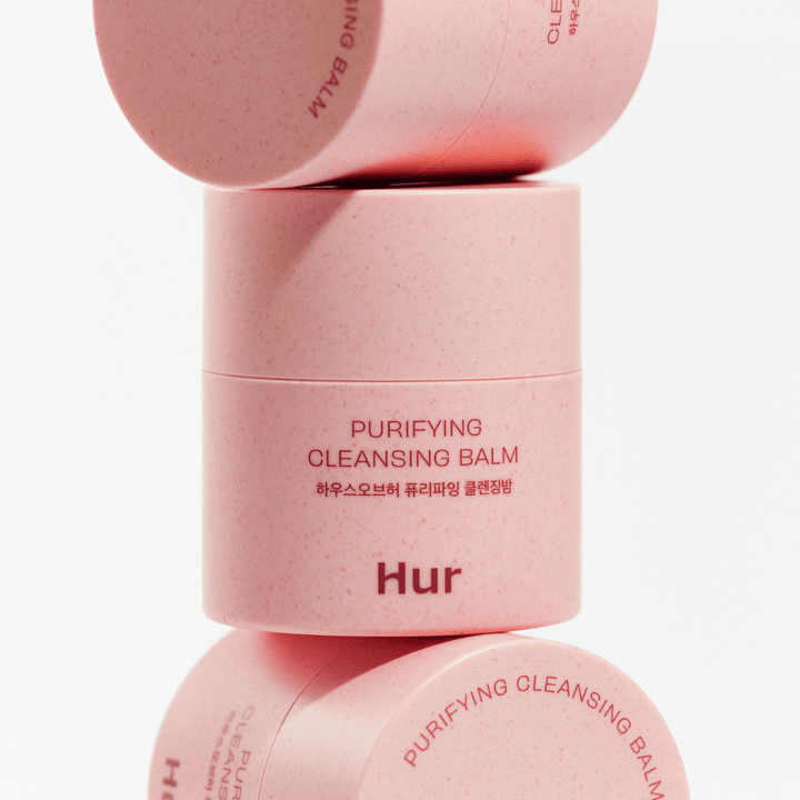 Hoe Purifying Cleansing Balm in roze verpakking gestapeld in studio. Reinigende reinigingsbalsem die effectief make-up, talg en onzuiverheden oplost zonder de huid uit te drogen.