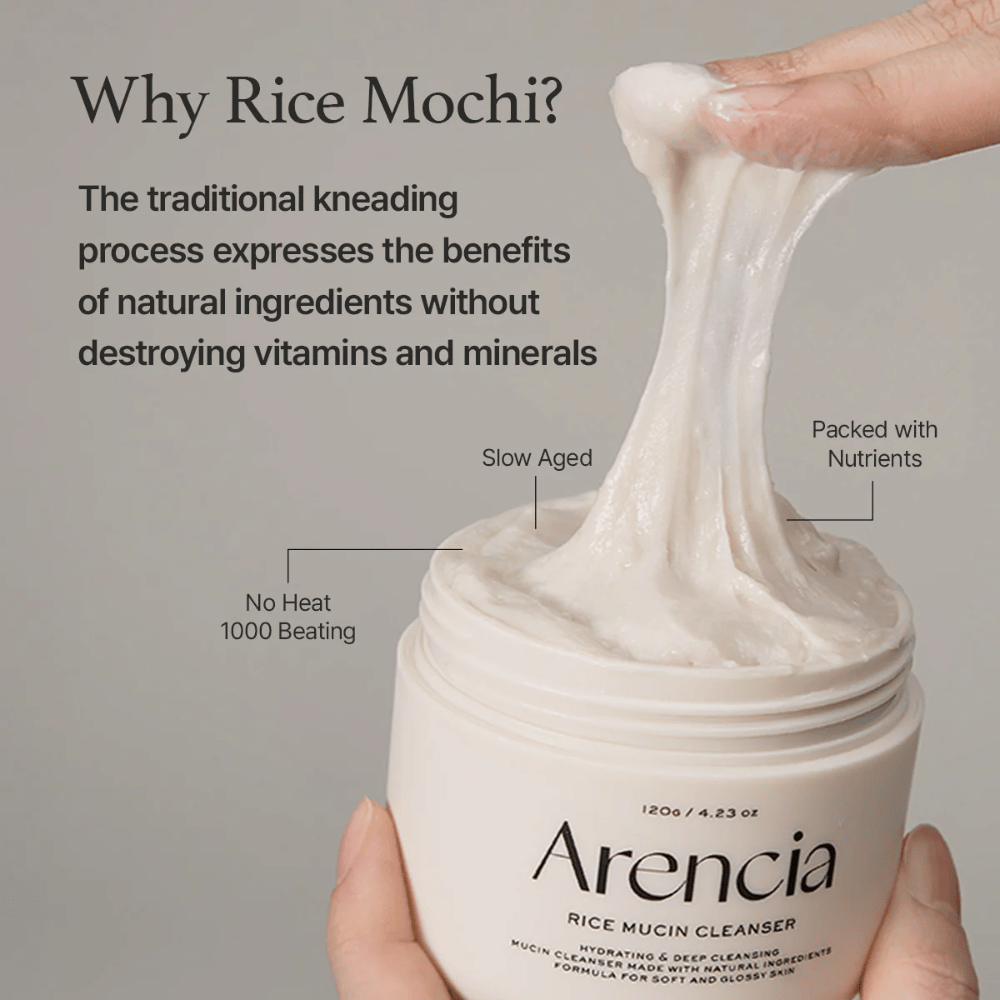 Hand die een elastische, witte reinigingscrème uit een pot tilt met het label "Arencia Rice Mucin Cleanser". De tekst beschrijft traditionele kneding die voedingsstoffen behoudt zonder vitaminen en mineralen te beschadigen.
