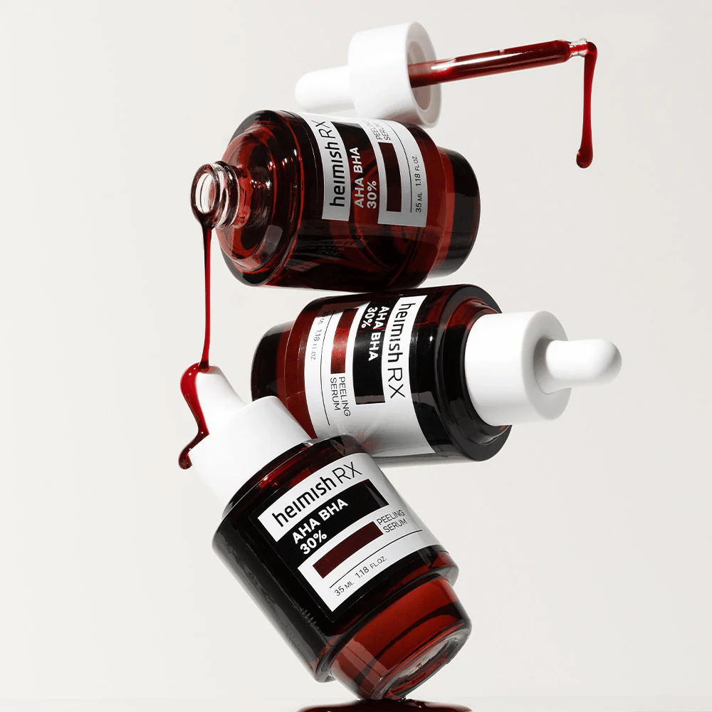 Drie flessen Heimish RX AHA BHA 30% Peeling Serum in een dynamische compositie, met rood gekleurd serum dat uit de pipetten druppelt.