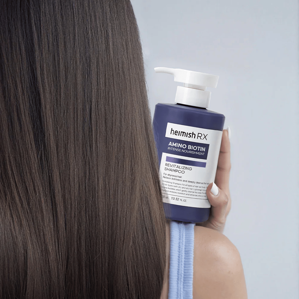 Heimish RX Amino Biotin Revitalizing Shampoo wordt in de hand gehouden tegen lang, glanzend haar – toont het resultaat van intensieve voeding en hydratatie voor droog haar.