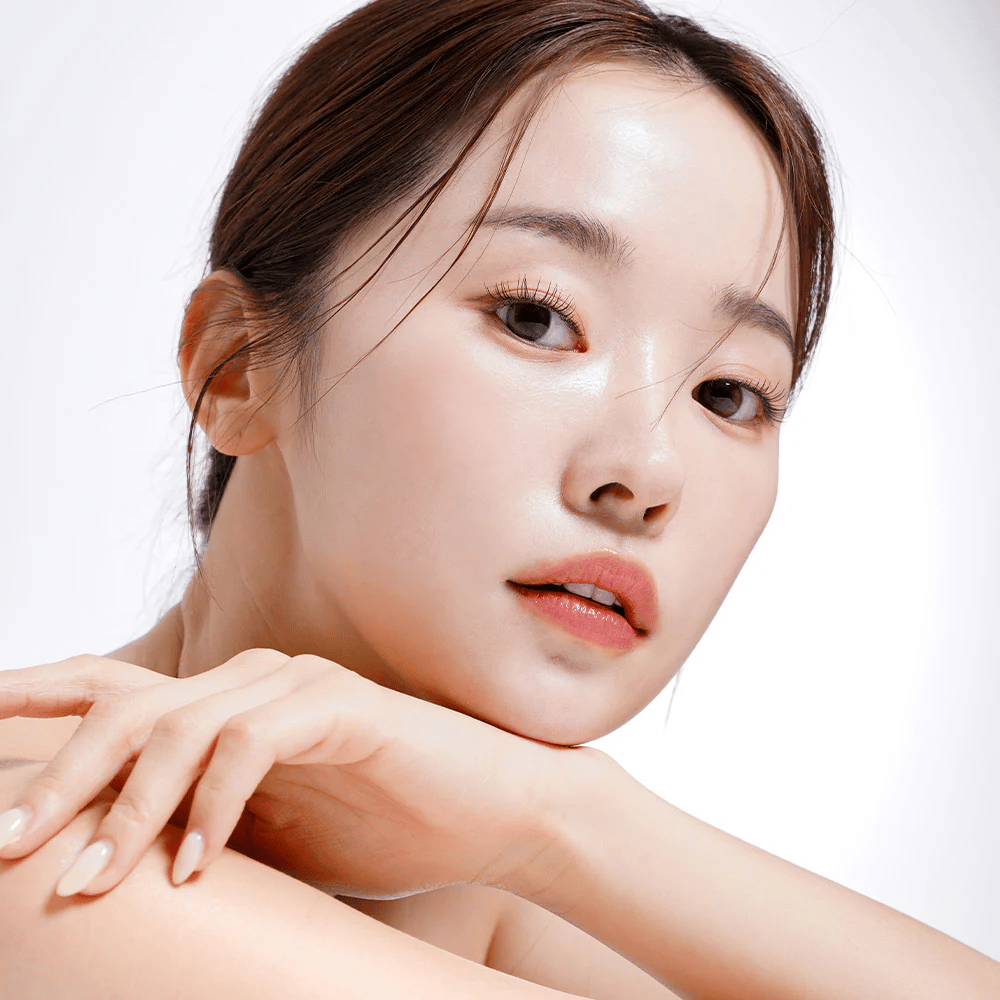 Close-up van een vrouw met stralende en gehydrateerde huid. Haar natuurlijke schoonheid wordt benadrukt door zachte verlichting, wat een frisse en gezonde uitstraling geeft.