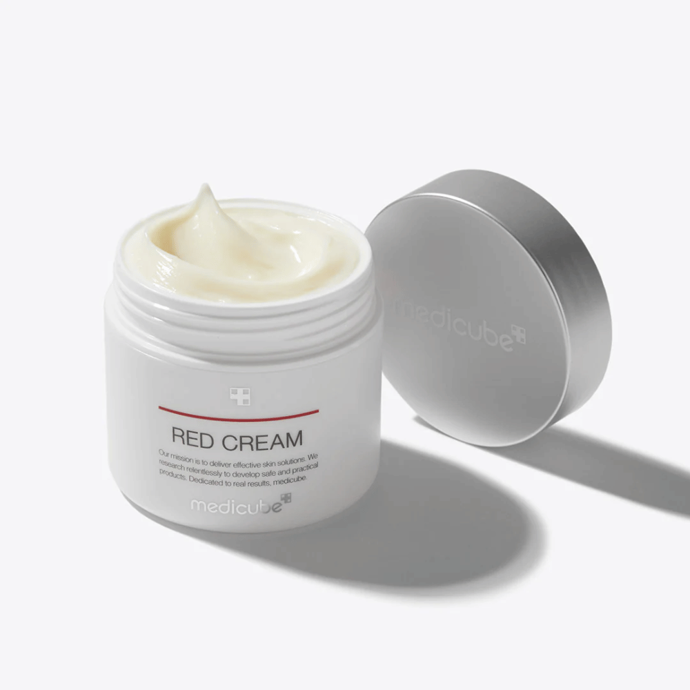 Open pot met medicube Red Cream 50ml – een lichtgele gezichtscrème in witte verpakking met zilveren deksel, ontwikkeld voor acne-gevoelige huid.